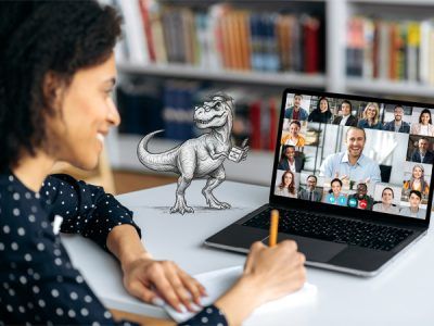 Mulher participando de mentoria online em videoconferência pelo notebook com o T-Rex acadêmico ilustrado sobre a mesa de estudos enquanto assiste à Mentoria Google Ads.